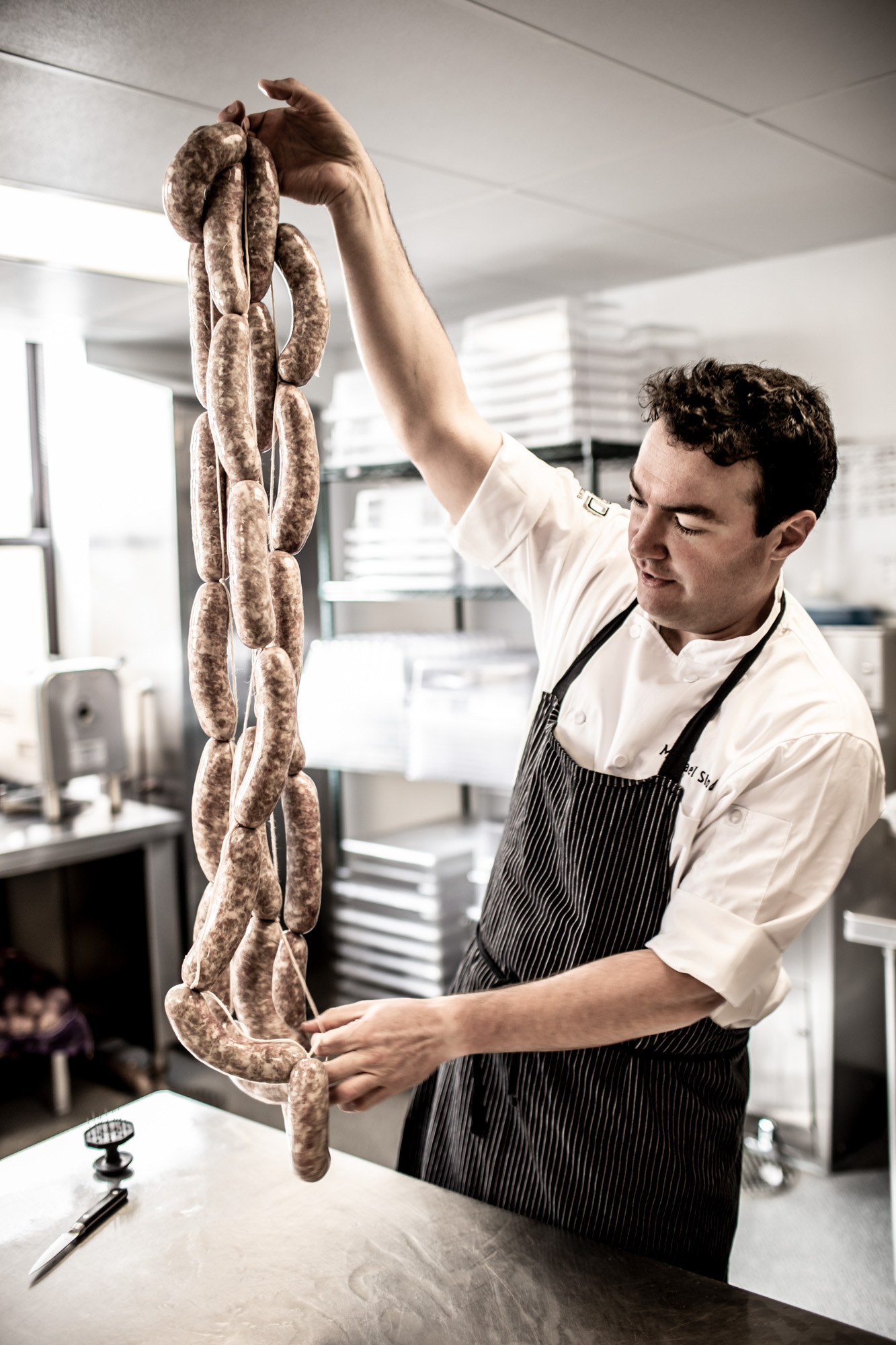 chef holding sausage links in kitchen