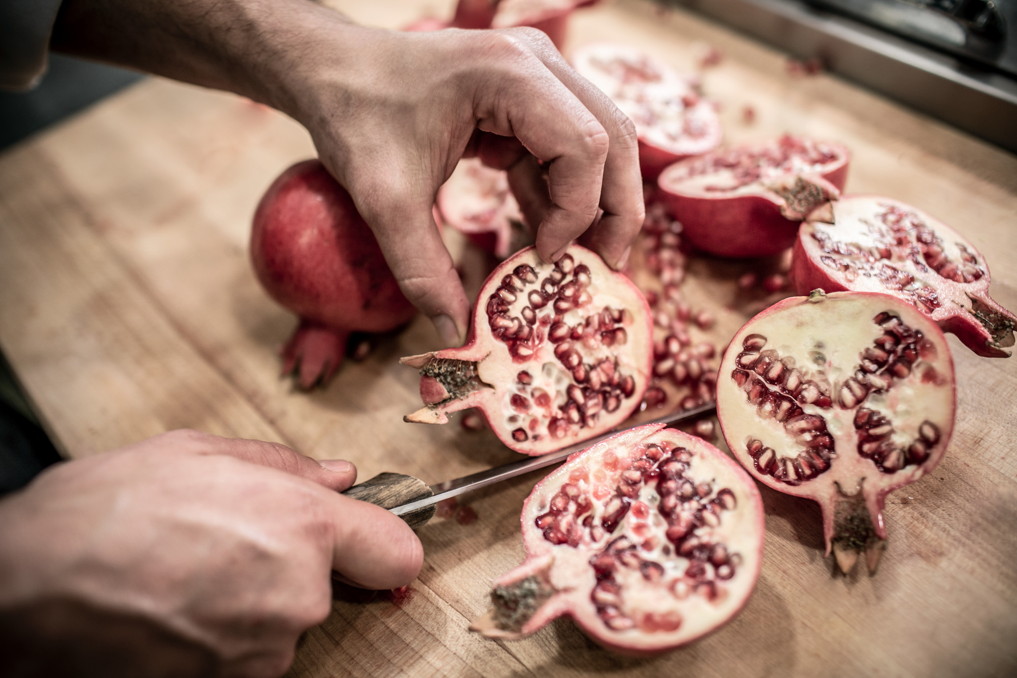 chef cutting pomegranate in kitchen