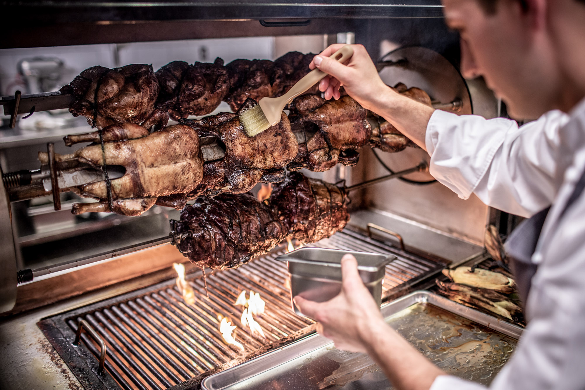chef basting chicken roasting on skewers