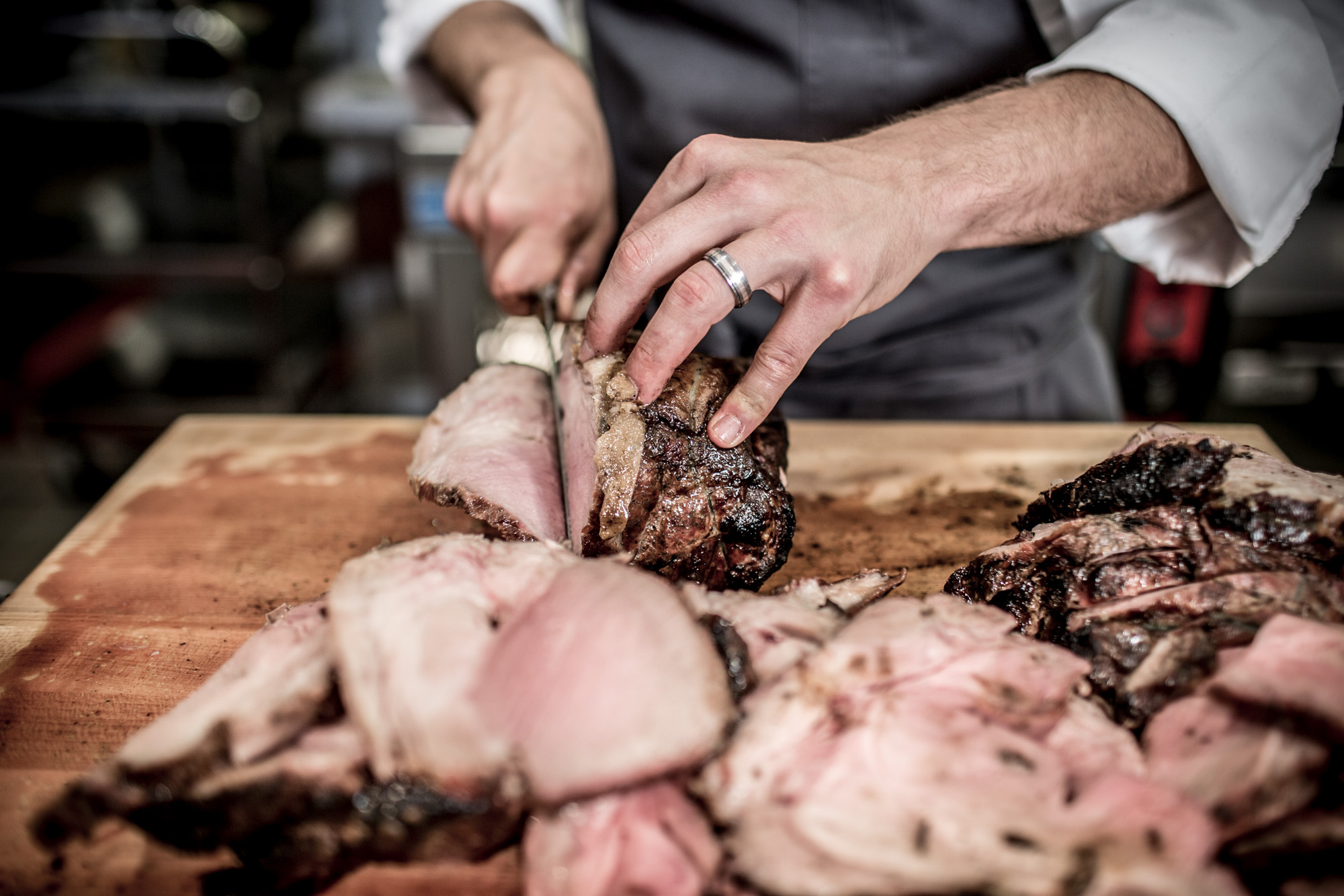 chef cutting up pork roast on cutting board