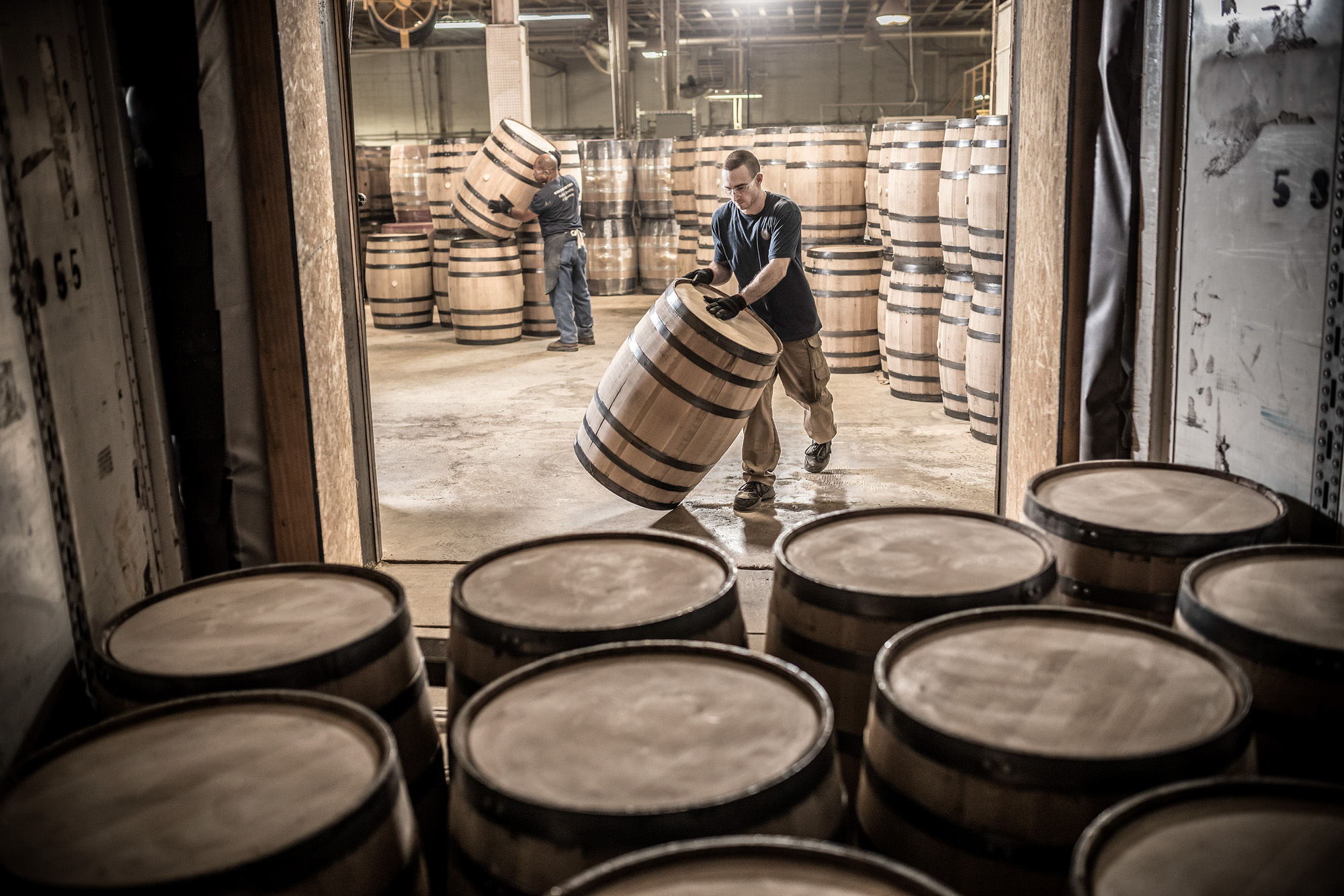 man men rolling wine whiskey barrels into truck at independent stave company plant in missouri