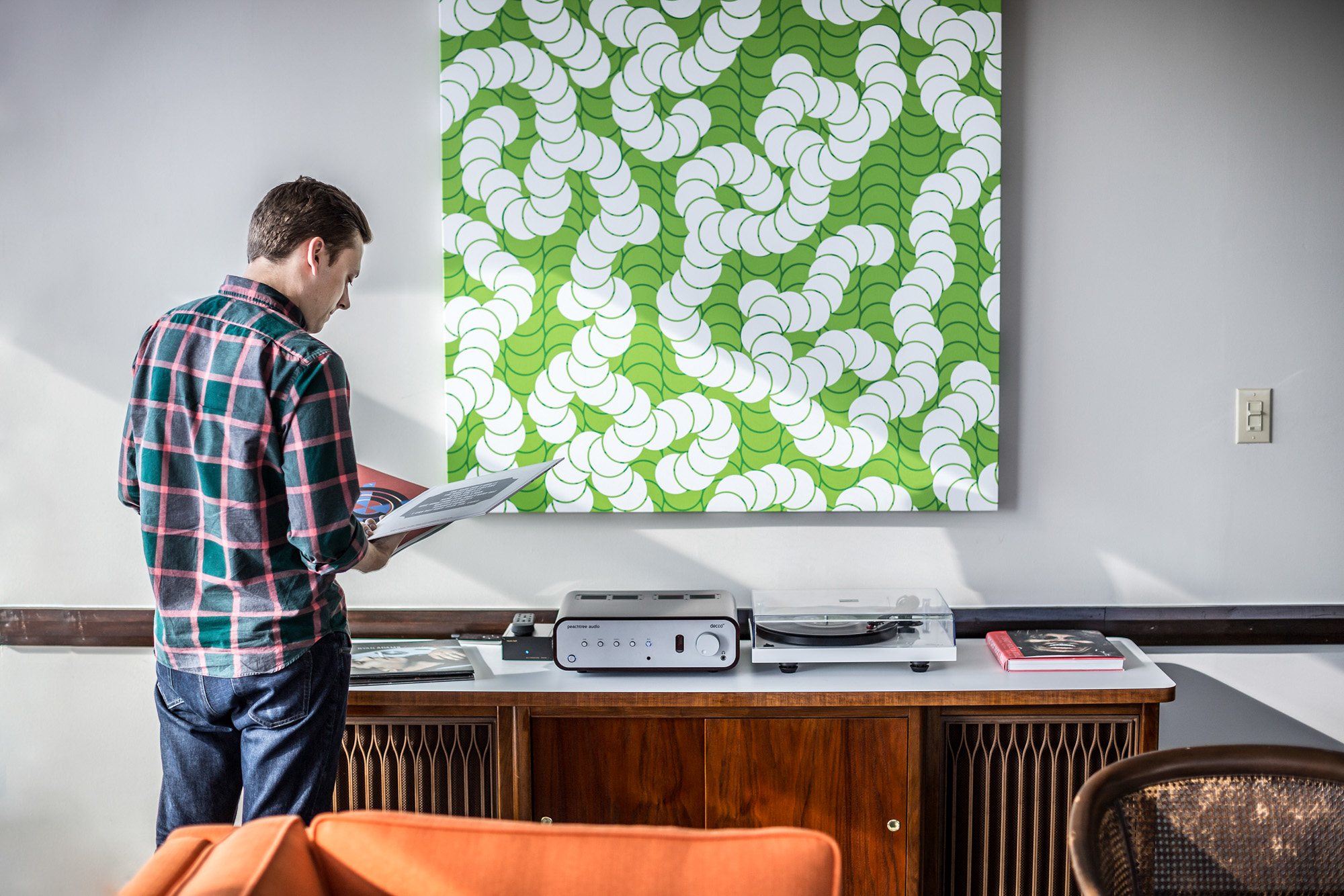man standing in office with vinyl record player and art work