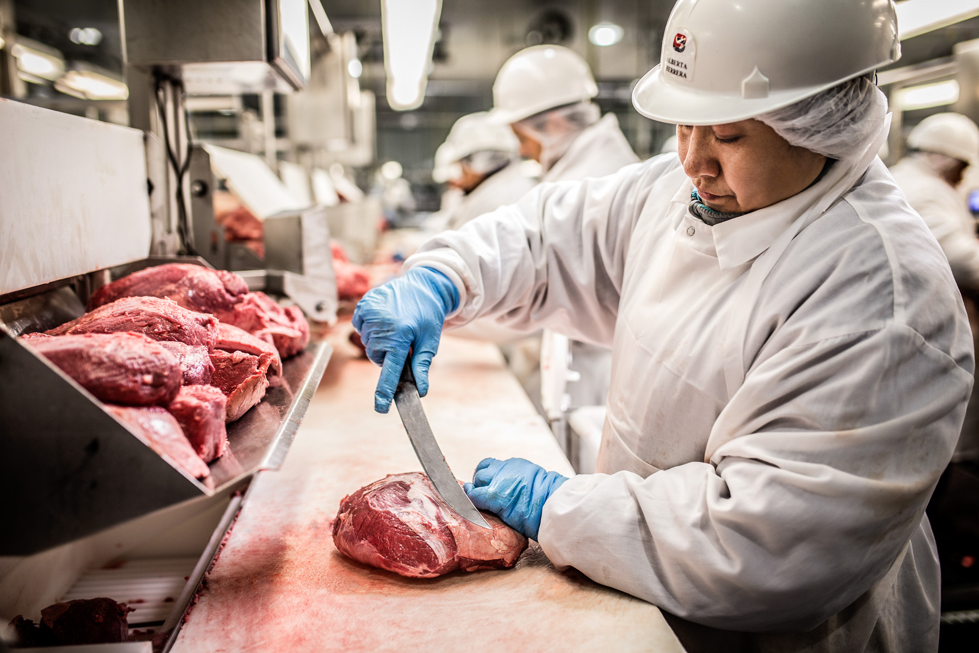one butcher woman slicing steak at standard meat facility in dallas tx