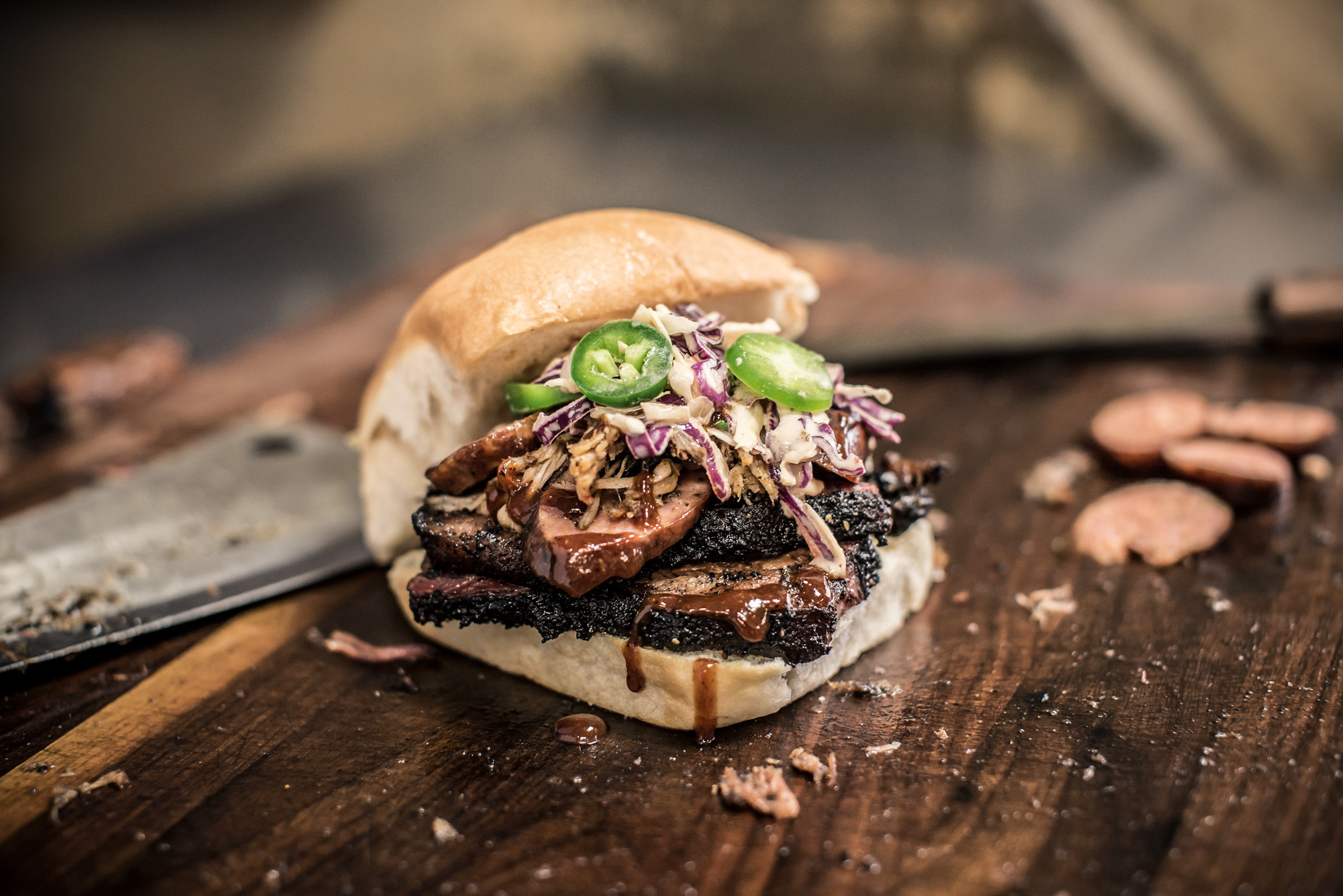 pecan lodge bbq sandwich sitting on wood table with brisket sausage coleslaw pit master sandwich