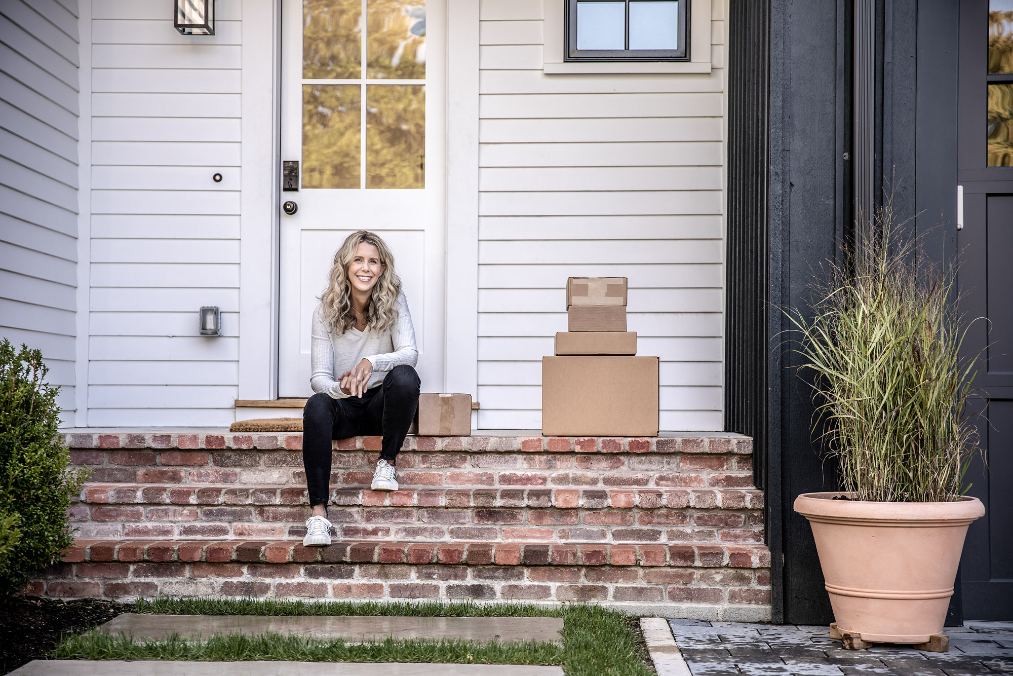 woman sitting on brick porch with boxes next to her at house home office
