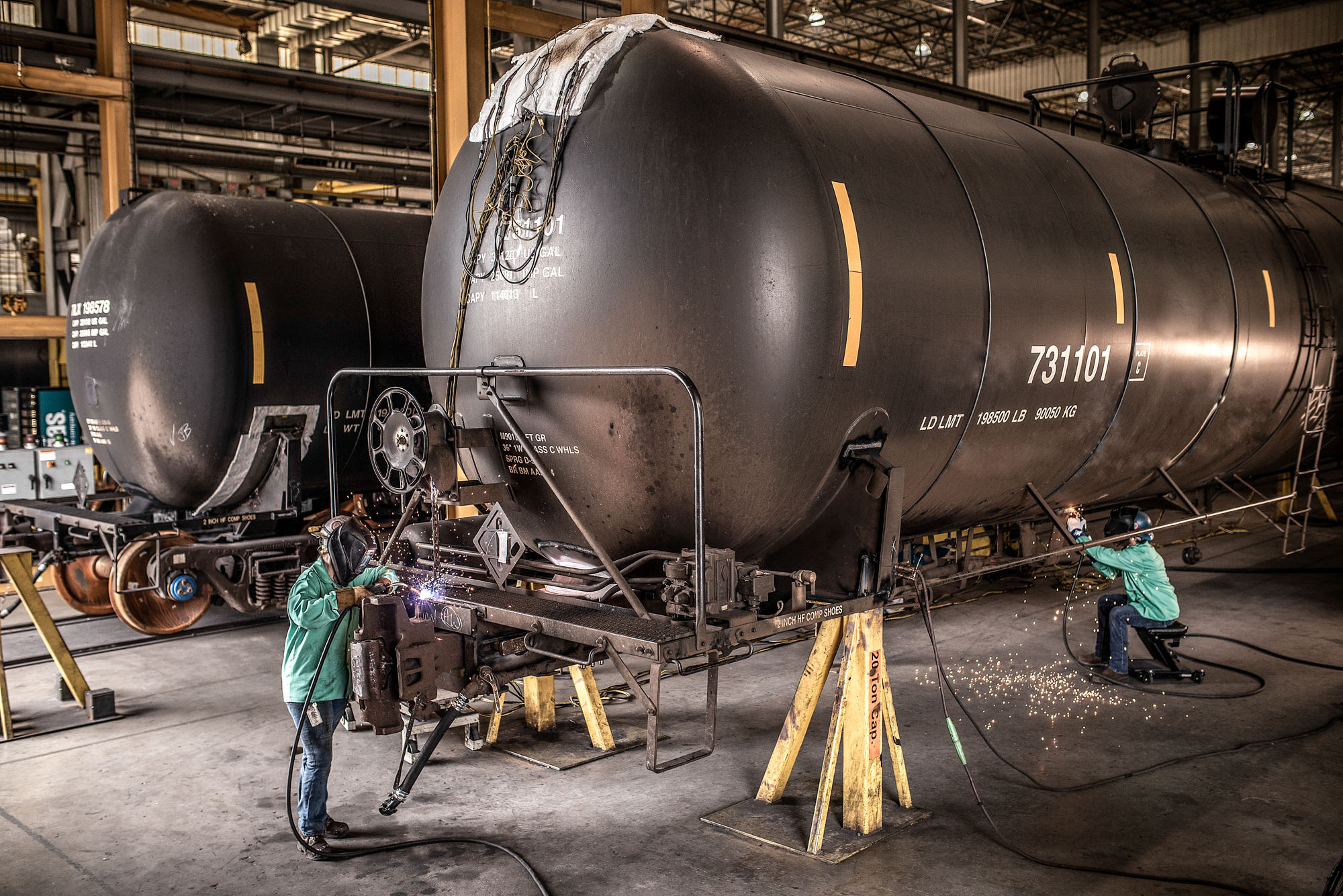 2 welders working on train tank car at industrial plant