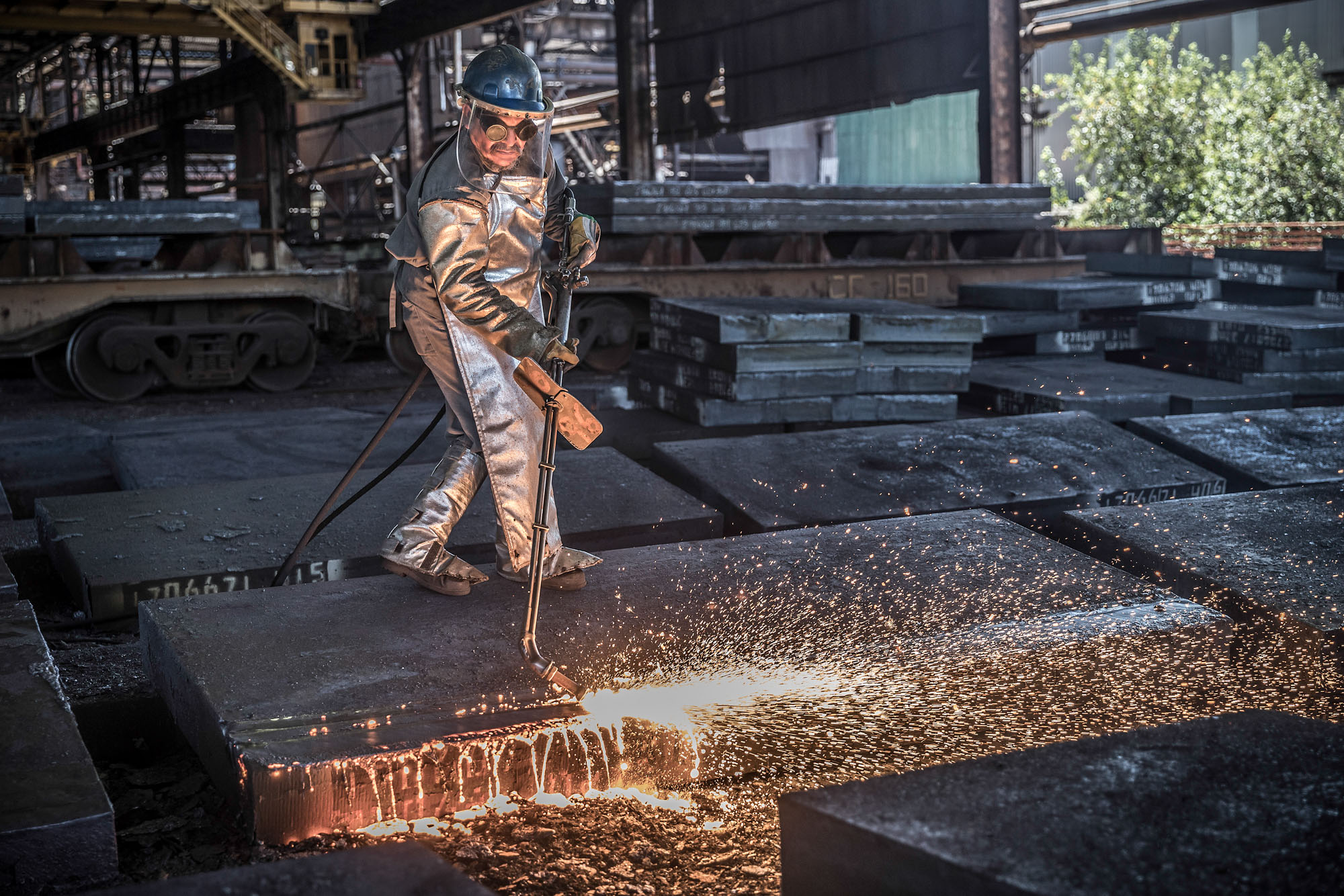 Steel worker man torching large blocks of steel