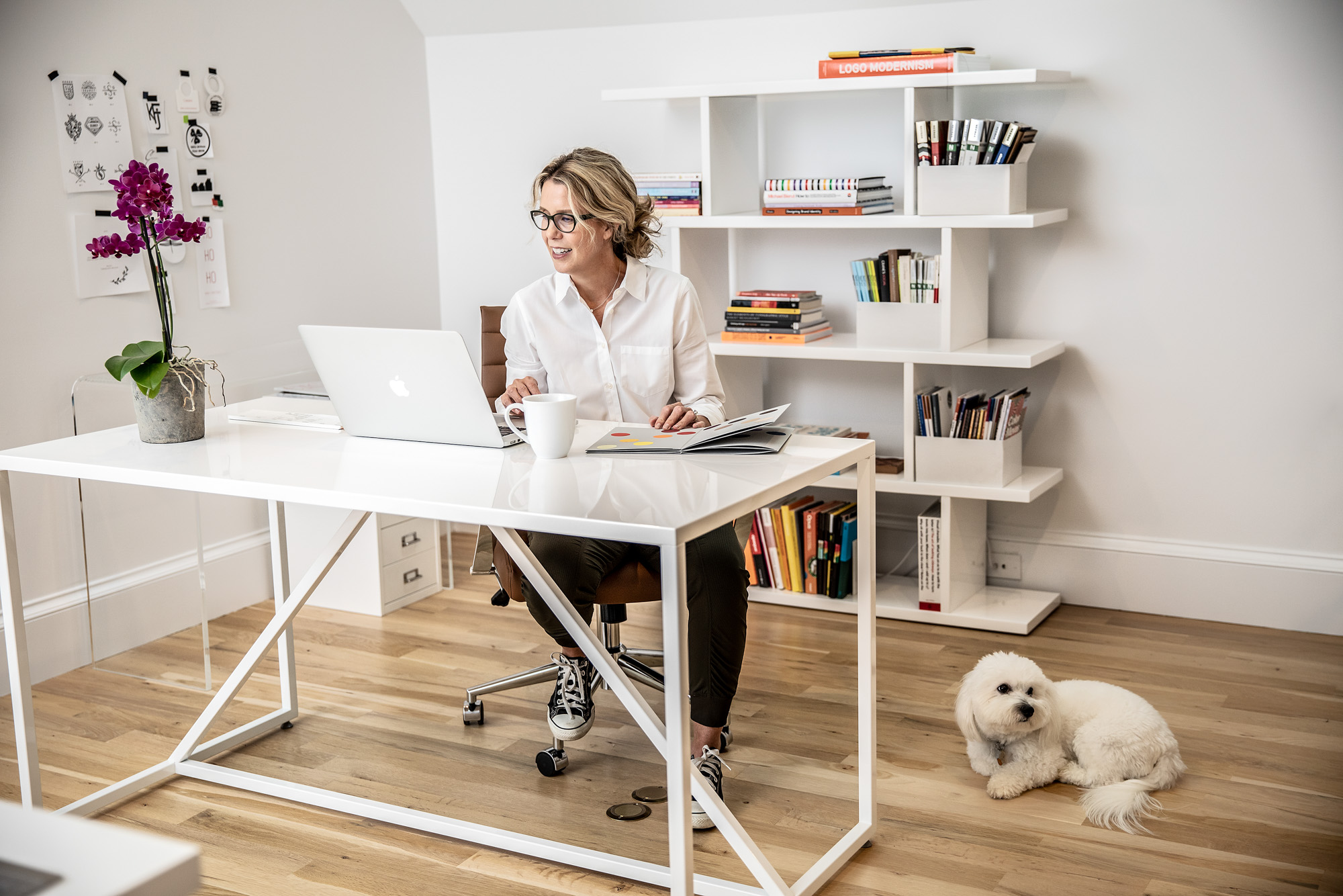 woman working at desk in home office with dog on floor